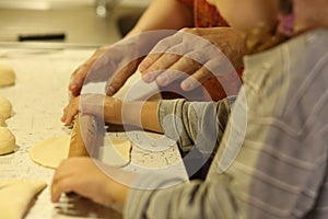 Ð girl rolls out the dough for pies with a wooden rolling pin. The hands of a little girl Ñaucasian close-up. We bake at home.